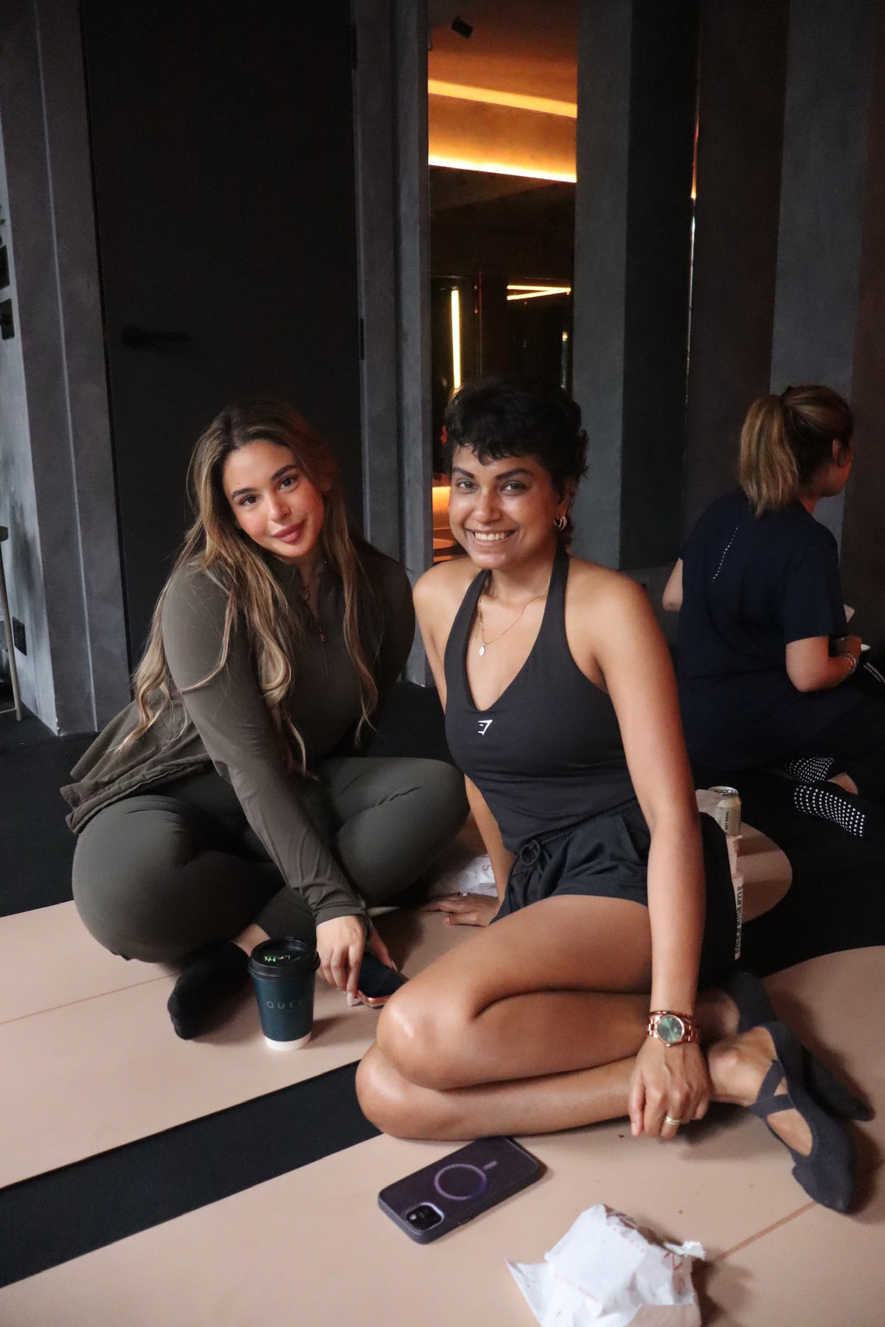 Two members smiling on their mats after class