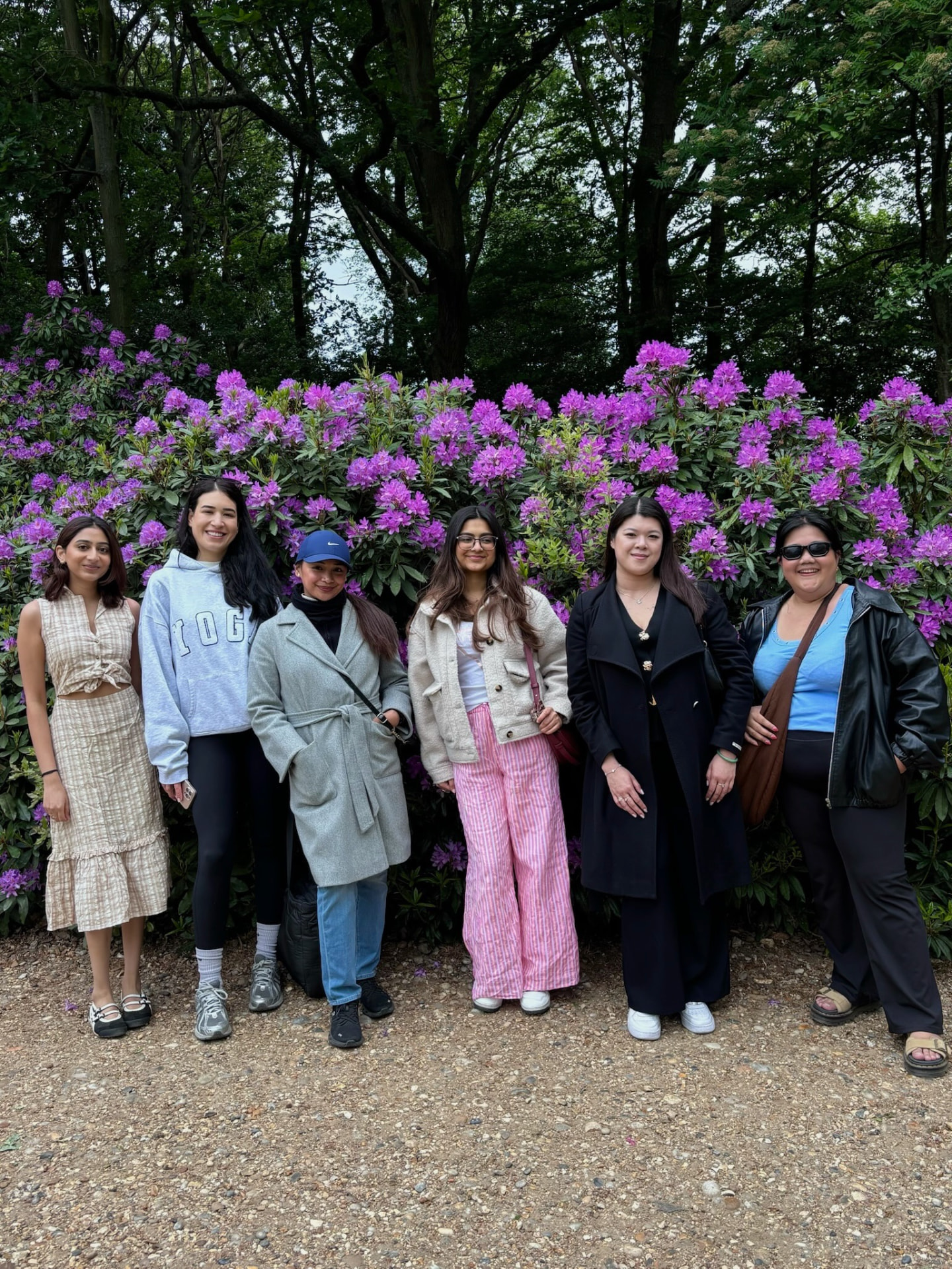 Group of members together outdoors in front of purple flowers